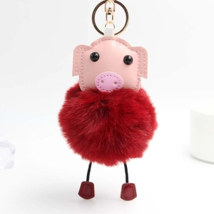 Détail de tête de porc en similicuir rose et pompon rouge avec fermoir métallique doré