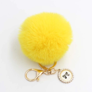 Close-up of fluffy yellow faux fur keychain with gold lobster clasp and pearl bow charm