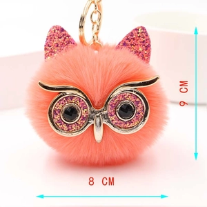 Détail d'un porte-clés hibou en peluche orange avec paillettes dorées, taille 9x8 cm