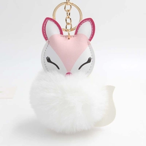 Detail of fox plush keychain featuring a soft white pom-pom and pink faux leather fox head