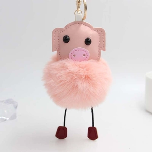 Détail d'un porte-clés cochon rose en peluche avec pompon doux et fermoir pivotant doré