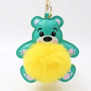Süßer Teddybär Schlüsselanhänger mit gelbem Bommel und blaugrünem Kunstleder