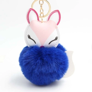 Close-up of sleeping fox keychain with dark blue plush fur ball and golden metal ring