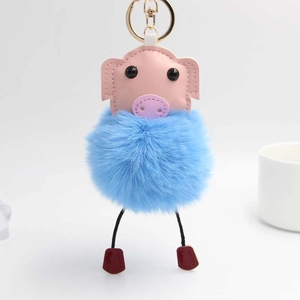 Détail d'un porte-clés cochon pompon bleu avec fermoir doré sur fond blanc pur