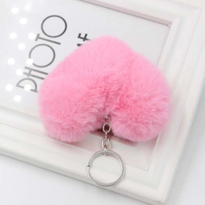 Primo piano di un portachiavi in peluche rosa a forma di cuore con anello in argento