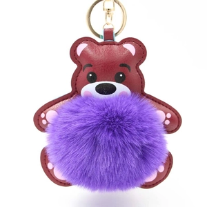 Detail von rotbraunem Leder-Bär-Schlüsselanhänger mit violettem Plüschball und Goldverschluss