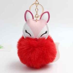 Detail of red faux fur pom-pom keychain with sleeping fox head and golden ring