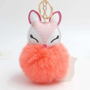 Detail of cute sleeping fox plush keychain with fluffy orange faux fur ball and golden clasp