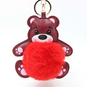 Nahaufnahme von dunkelrotem Teddybär-Schlüsselanhänger mit flauschigem Bommel und Goldclip