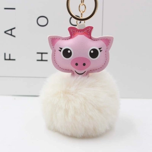 Détail d'un porte-clés cochon en similicuir rose avec pompon en peluche blanche et anneau doré