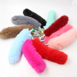 Flat lay of colorful faux fur fox tail keychains in nine vibrant shades with metal rings