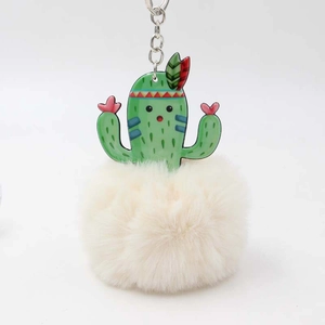 Close-up of a cute green cactus plush ball keychain with a white fluffy fur pom and silver clip
