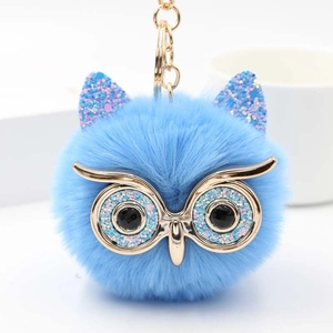 Détail du porte-clés hibou en peluche bleue avec oreilles à paillettes et yeux en métal doré