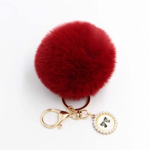 Detail of red plush ball keychain with golden clasp and pearl bow pendant decoration