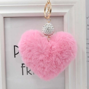 Dettaglio del portachiavi a cuore in pelliccia sintetica rosa con perla di strass e anello d'oro