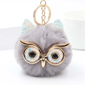 Détail du porte-clés hibou en pompon avec fourrure grise et finitions dorées brillantes