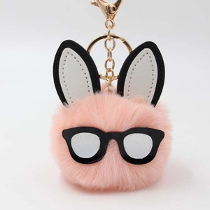 Close-up of pink fluffy rabbit pom-pom keychain with black glasses and gold alloy clasp