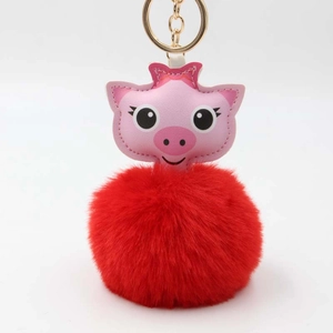 Vue détaillée du porte-clés boule de fourrure rouge avec breloque cochon en cuir rose