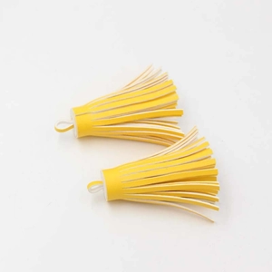 Macro shot of two bright yellow PU leather tassel charms for handbags and keychains