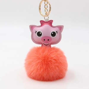 Vue détaillée d'un porte-clés cochon rose avec un pompon en peluche corail soyeux