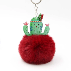 Detail showing green acrylic cactus charm and deep red fluffy faux fur pompom keychain