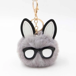 Detailed view of plush rabbit pompom keychain with chic glasses and golden hook