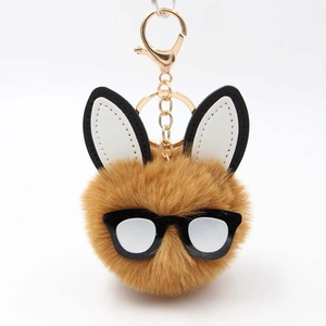 Detailed macro view of the fluffy rabbit pompom keychain with chic black glasses