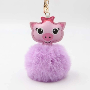 Détail du porte-clés cochon en cuir rose avec pompon en fausse fourrure violette et anneau doré