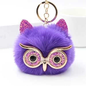 Gros plan sur un porte-clés hibou en peluche violette avec paillettes et anneau doré