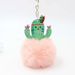 Detail of a fluffy pink faux fur pompom and green acrylic cactus keychain with silver ring