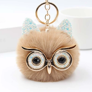 Détail d'un porte-clés hibou en peluche avec yeux à paillettes et anneau doré brillant
