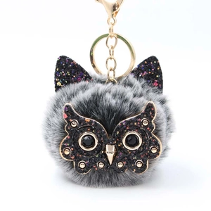 Detail of owl plush keychain with fluffy grey faux fur and shimmering sequins