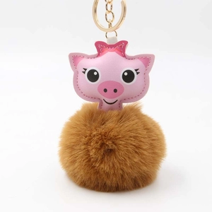 Vue détaillée du porte-clés pompon cochon rose avec anneau doré et boule de fourrure douce