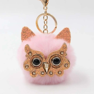 Detail of pink faux fur owl keychain with gold glitter face and sparkling gemstone eyes