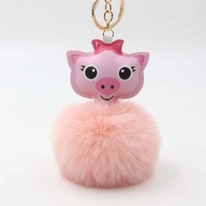 Détail d'un porte-clés pompon en peluche rose avec cochon de dessin animé et clip doré