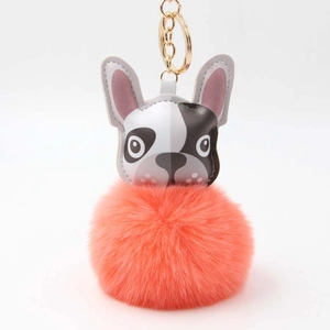 Detailaufnahme von flauschigem orangefarbenem Kunstfell-Bommel und Hundekopf-Anhänger