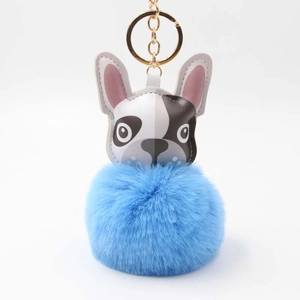 Detail eines blauen Pelz-Pompon-Schlüsselanhängers mit Bulldogge-Motiv und Goldring