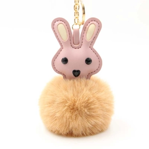 Detail of pink faux leather rabbit keychain with soft brown pompom and gold metal ring