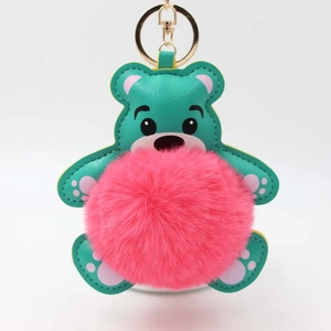 Detail eines blauen Teddybär-Schlüsselanhängers aus Leder mit rosa Plüschball und Goldclip