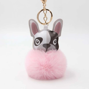 Detailansicht eines flauschigen rosa Bommel-Bulldoggen-Schlüsselanhängers mit Goldkarabiner