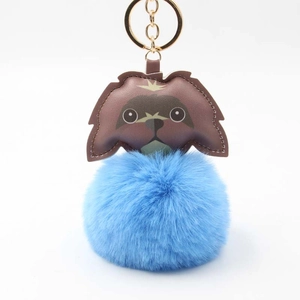 Detail of cute puppy plush keychain with blue fur pompom and golden metal ring hook