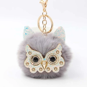 Fluffy grey owl keychain featuring a plush pompom and gold-tone owl face with black gems