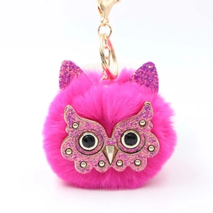 Detail of a fluffy pink pom-pom owl keychain with sequins and a golden metal clasp