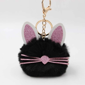 Detail of black faux fur pompom keychain with pink glitter rabbit ears and gold clasp