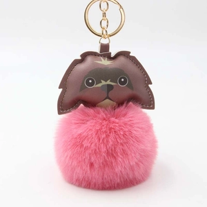 Detailed view of pink faux fur ball keychain with brown puppy leather patch and gold ring