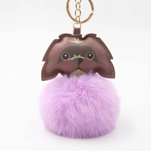 Detail showing a purple pom-pom keychain with a brown leather dog head and gold hardware