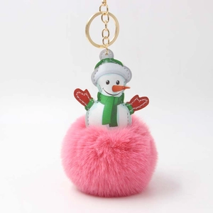 Detail eines rosa Bommel-Schneemann-Schlüsselanhängers mit Goldring auf weißem Hintergrund