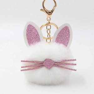 Detail of white fluffy cat fur ball keychain with pink glitter ears and gold clasp