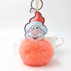 Close-up of fluffy coral plush pompom keychain with cartoon Santa Claus leather charm