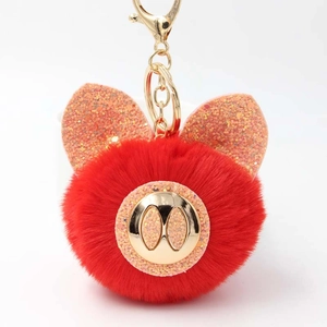 Détail macro d'un porte-clés cochon en peluche rouge avec oreilles pailletées dorées